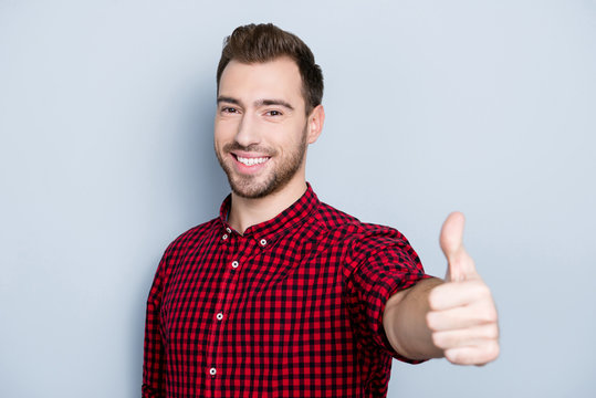 Well done! Great job! Portrait of cheerful excited with toothy beaming smile glad businessman dressed in red checkered shirt, he is presenting thumb-up to you, isolated on gray background