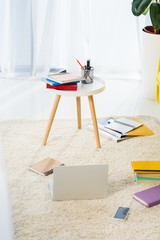 close up view of laptop, notebooks and folders arranged on floor at home office