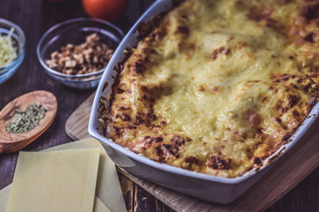 lasagne layered served on a wooden board with fresh tomatoes alongside