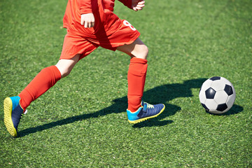 Child soccer player and ball on football field