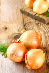 Yellow onion with parsley on a wooden table.