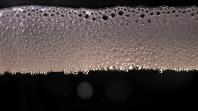 White bubbles floating on a beer liquid. slow motion