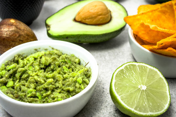 Traditional mexican sauce - guacamole dip with avocado and tortilla chips snack on table, party food for sharing