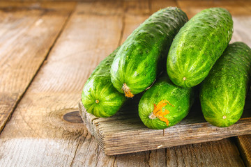 Fresh cucumbers with a leaf on an old wooden table.