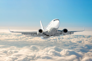 White airplane flies climbs height, flight level high in the sky above the clouds blue sky.