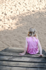blondes mädchen auf dem spielplatz im sand