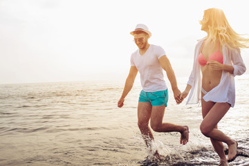 Romantic couple having fun on the beach. Happy couple running on beach at sunset.
