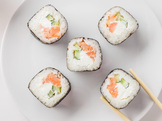 Japanese restaurant, sushi roll on white plate. Set for one person with chopsticks, ginger, soy, top view, copy space