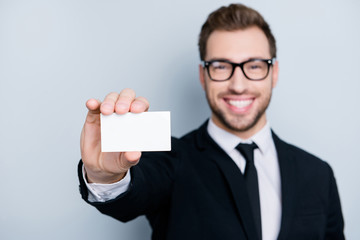 Close up photo of excited handsome cheerful young elegant smart man giving a call card, isolated on gray background, copyspace