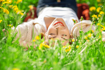 beautiful woman lies in a summer meadow and relaxes in the sun