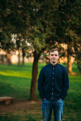 A young man in a park in a dark blue shirt. Spring