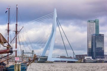 Obraz premium Cityscape - view of the moored sailboat on a background of skyscrapers district Feijenoord city of Rotterdam and the Erasmus Bridge, The Netherlands