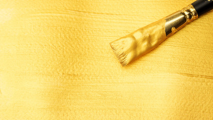 Paintbrush on a gold colored poster watercolor.