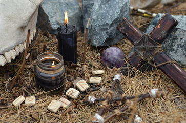Wooden cross, old runes, pentagram and black candles. Mystic background with ritual esoteric objects, occult and halloween concept
