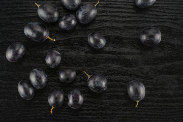 Black grape berries (autumn royal variety) table top isolated on black wood background.