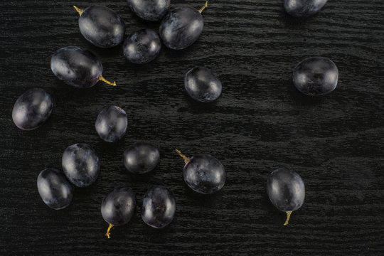 Black grape berries (autumn royal variety) table top isolated on black wood background.