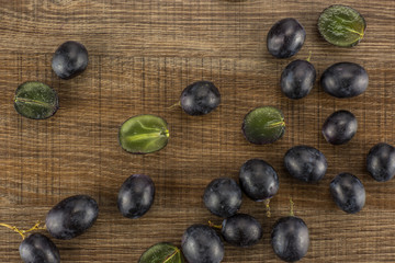Black grape berries (autumn royal variety) table top isolated on brown wood background some sliced.