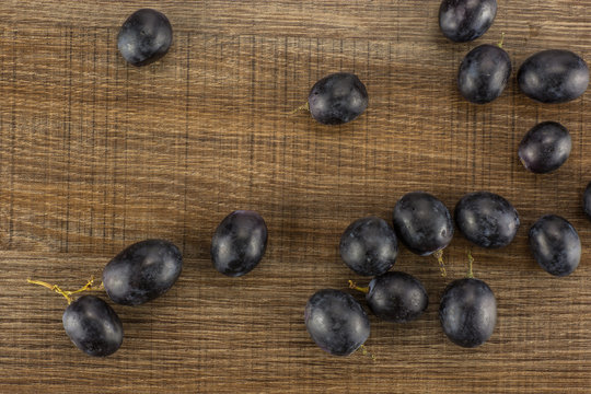 Black grape berries (autumn royal variety) table top isolated on brown wood background.