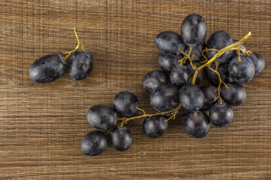 Black grape cluster (autumn royal variety) with berries table top isolated on black wood background.