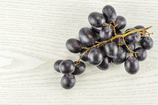 Black grape cluster (autumn royal variety) table top isolated on grey wood background.