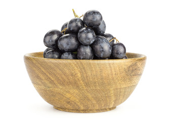 Black purple grape cluster (autumn royal variety) in a wooden bowl isolated on white background.
