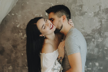 Amazing couple having fun embracing where man is kissing on girls neck while she is laughing with closed eyes.