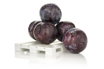Five red blue plums on a wood pallet isolated on white background round whole fresh juicy fruit.