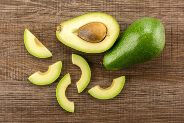 Green smooth avocado sliced composition table top isolated on brown wood background bacon variety.