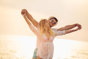 Fototapeta na wymiar Romantic couple having fun on the beach. Happy couple running on beach at sunset.