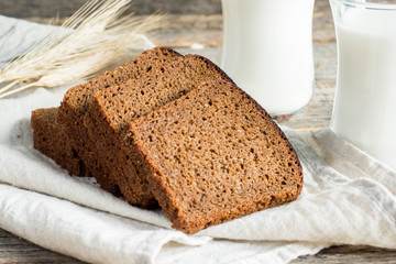 Fresh healthy milk in glass cups and sliced cereal bread on a wooden rustic background