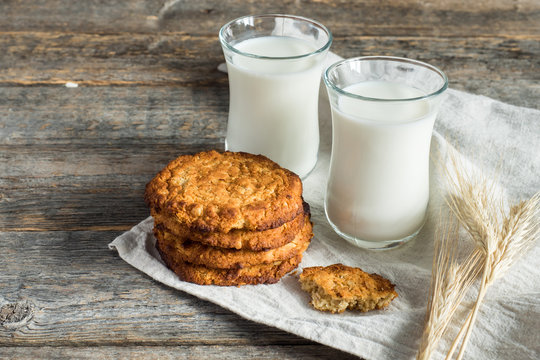 Fresh healthy milk and oatmeal cookies with cereals on wooden rustic background