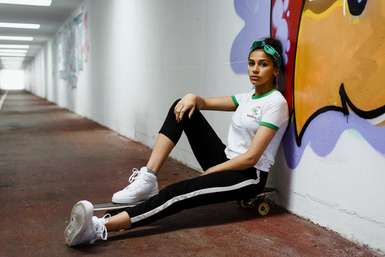 Portrait of young woman sitting on skateboard