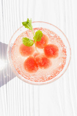 Frozen watermelon balls in a glass of mineral water with beautiful shadows, refreshing drink, clean eating,balance and healthy food and diet  concept
