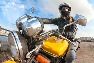 Wide angle view at young woman motorcyclist sitting on bike, focus on girl