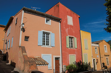 Fototapeta na wymiar View of traditional colorful houses in ocher under a sunny blue sky, in the city center of the village of Roussillon. Located in the Vaucluse department, Provence region, in southeastern France
