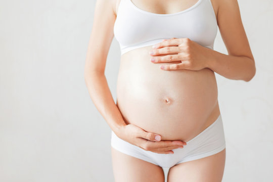 Pregnant woman in white underwear. Young woman expecting a baby.