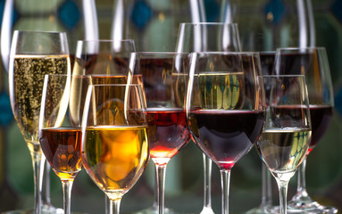 Champagne, white and red wins and drinks in glasses on stained glass background