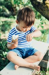 a child in a t-shirt on a bench eating ice cream in the summer is very greedy