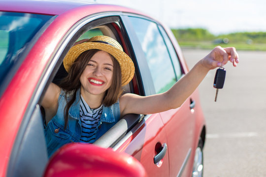 Driver woman smiling showing new car keys and car. Happy woman driver showing car keys and leaning on car door
