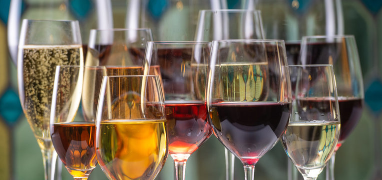 Champagne, white, rose and red wins and drinks in glasses on stained glass background
