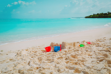 Sand castle and toys on tropical beach