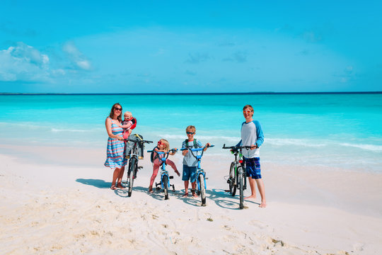 Happy Family With Kids Riding Bikes On Beach