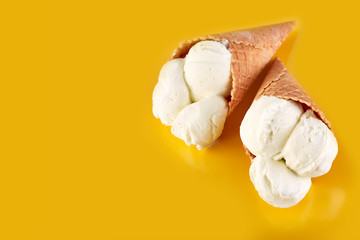 ice cream balls in a Waffle Cone on a yellow Background. Vanilla ice cream in a waffle cone.