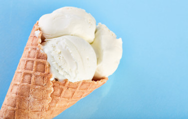 ice cream balls in a Waffle Cone on a Blue Background. Vanilla ice cream in a waffle cone.