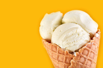 ice cream balls in a Waffle Cone on a yellow Background. Vanilla ice cream in a waffle cone.