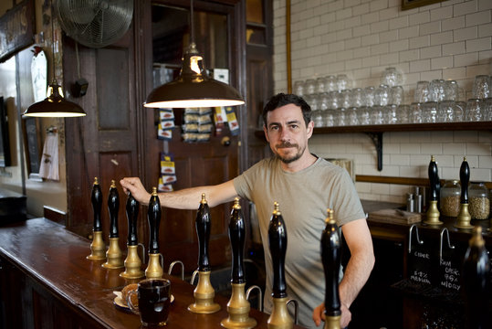 Portrait of man behind beer tap in pub