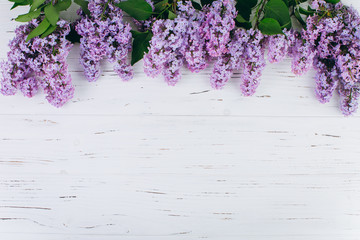 The beautiful violet lilac on a white wooden background. Flat lay and copy space composition.