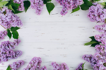 The beautiful violet lilac around a white wooden background. Flat lay and copy space composition.