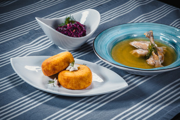 Set of three dishes. Business lunch of three dishes. Three dishes on white plates on a table with a blue tablecloth striped. Soup, salad and hot dish.