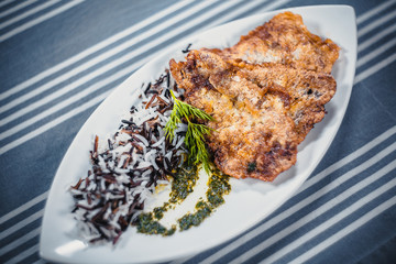 Top view of cutlets from pike with rice on a white plate. Plate on the table with a blue tablecloth in white strips.
